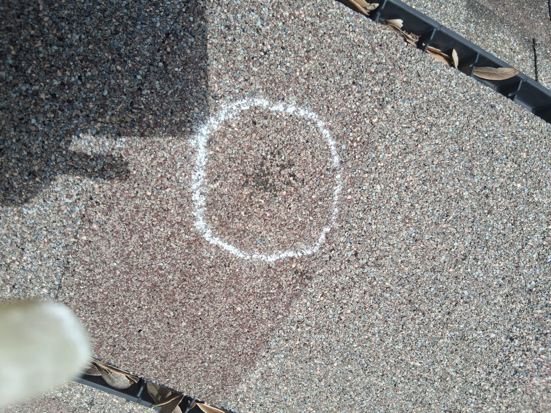 Hail impact on asphalt shingles marked with chalk during a storm damage inspection