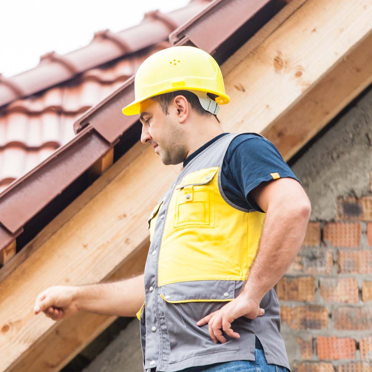 Roofer inspecting the roof edge and gutter line during a roof maintenance visit in Fort Bend County